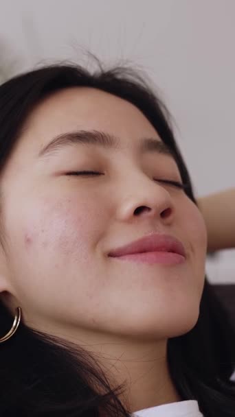 自宅でソファでリラックス頭の後ろに手を持つ若い機械の女性の垂直ショット Joyful Chinese Ethnicity Female Daydreaming Couch — ストック動画