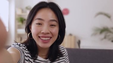 POV mutlu genç Asyalı kız akıllı telefon ağı uygulaması ile evde video görüşmesi yapıyor. Neşeli Çinli bir kadın cep telefonuyla video konferansında konuşuyor.