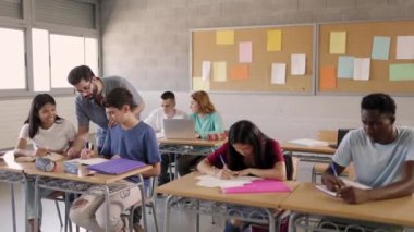 Male teacher helping students in classroom - Education concept