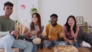 Mutlu genç arkadaşlar kanepede oturup evde birlikte televizyon izliyorlar. Genç bir grup insan birlikte eğleniyor. Sosyalleşiyorlar, pizza yiyorlar ve oturma odasında bira içiyorlar.. 