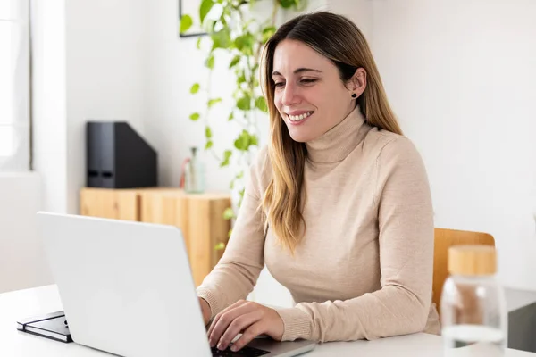 stock image Happy young smiling woman working on laptop from home office. Business female entrepreneur sitting on desk typing on computer