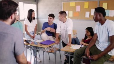 Erkek öğretmen ve genç öğrenciler ders aralarında konuşurlar - farklı milenyum insanlarından oluşan mutlu bir grup okulda öğretmenle takılır