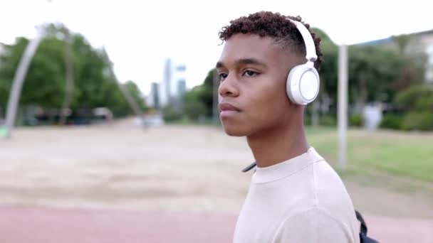 若いですヒスパニックラテンティーン男の子歩く屋外で音楽を聞きながら 無線ヘッドフォン — ストック動画