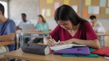 Lisedeki sınıfta egzersiz yapan Asyalı genç kız öğrenci. Yüksek kalite 4k görüntü