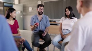Erkek öğretmen ve çeşitli öğrenciler beyin fırtınası sırasında birlikte çalışıyorlar. Akademik proje için yeni fikirler üreten bir grup genç sınıf lisesinde hoca daireler çiziyor..