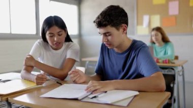 Lisede birlikte çalışan iki çok ırklı genç öğrenci. Latin kız ve beyaz çocuk sınıfta akademik proje hakkında tartışıyorlar.. 