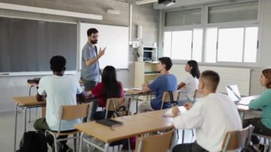 Genç erkek öğretmen okuldaki çok ırklı genç öğrencilere ders veriyor. Eğitim kavramı