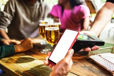 Müşteri faturayı ödemek için cep telefonu kullanıyor. Genç adam, iletişim teknolojisiyle birkaç bira öderken beyaz ekranla akıllı telefonu tutuyor. Mobil ödeme kavramı