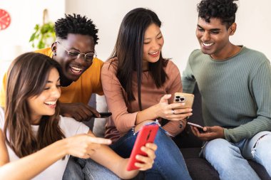 Bir grup farklı genç evde akıllı telefon kullanarak eğleniyor. Sosyal medya uygulamasında cep telefonundan medyayı izleyen çok ırklı öğrenci arkadaşlar. Teknoloji yaşam tarzı ve gençlik kavramı