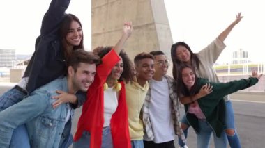 Genç çoklu etnik arkadaşlar açık havada grup fotoğrafı çektirmek için birlikte eğleniyorlar. Milenyum çeşitliliği olan insanlar birlikte fotoğraf çektirirken tatilden zevk alıyorlar. Arkadaşlık kavramı