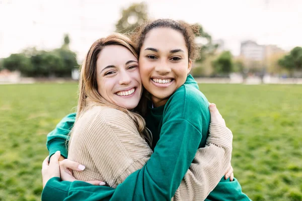 公園で抱き合って幸せな若い多民族の女性の親友の肖像画 — ストック写真