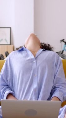 Genç, Latin Amerikalı bir kadının evde dizüstü bilgisayar kullanırken çekilmiş dikey videosu. Oturma odasında kanepede otururken internette sörf yapan gülümseyen genç bir bayan. HD ekran görüntüleri