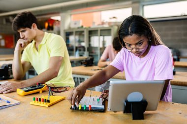 Latin kökenli genç kız öğrenci lise dersinde elektronik öğreniyor. Eğitim yaşam tarzı kavramı