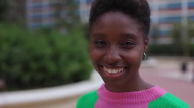 Açık havada kameraya bakan gülümseyen Afrikalı genç bir kadının yakın plan portresi. Çeşitli mutlu insanlar konsepti