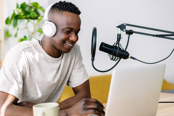 Молодой творческий мужчина африканский подкастер делает живой радиоподкаст из домашней студии