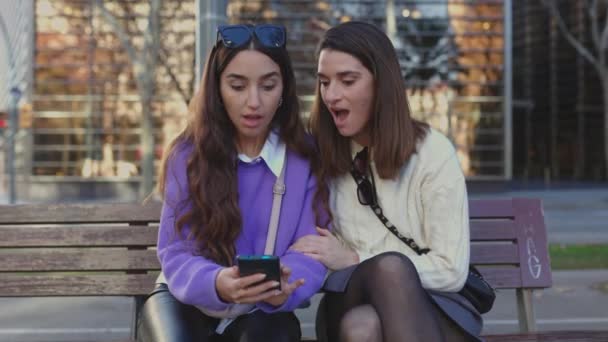 何百万人もの女性の友人がスマートフォンの画面で良いニュースを読んでいます 携帯電話で信じられないほどのメッセージを受け取る若い女性 — ストック動画