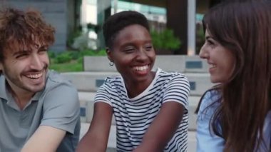 Three young diverse student people laughing together having fun outdoors. Community, diversity and unity concept.
