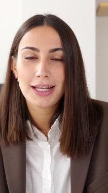 Vertical footage POV screen view of beautiful young business woman talking on laptop video call in the office. Smart entrepreneur female looking at camera having a conversation on virtual meeting.