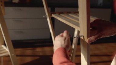 Close up view of young man assembling new furniture in the morning at home. High quality 4k footage