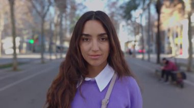 Young latin american trendy woman looking at camera smile in city urban background. Millennial happy portrait of cheerful female outdoors.