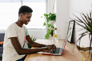 Young adult black woman working remotely at home using laptop computer