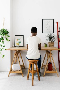 Vertical shot rear view of creative trendy young african american woman working on laptop at home studio office - Freelancer and entrepreneur people concept