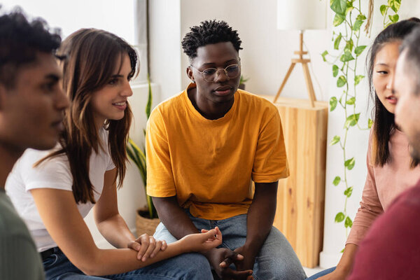 Multiracial people sitting in circle during group therapy supporting each other. Diversity, mental health and support concept. People communicating while sitting in circle and gesturing.