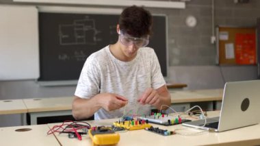 High school student man learning to build electronic circuits at technology class. Education concept