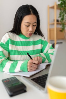 Vertical young asian student woman using laptop studying online at home. Millennial chinese female listening on training class meeting video call