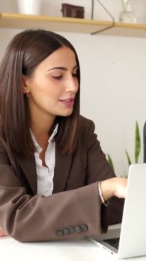 Vertical video of young trendy businesswoman working with colleague on laptop in creative office. Coworkers team discussing about new project at work.