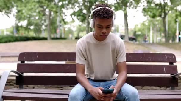 Şehir Parkında Bankta Cep Telefonu Kullanan Genç Latin Amerikalı Çocuk — Stok video