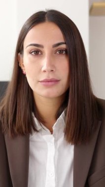 Masada oturan ciddi iş kadınının kendine güvenen video portresi. Kameraya bakan güzel bir bayan girişimcinin ön manzara portresi. Başarılı insanlar konsepti