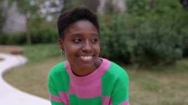 Gülümseyen genç Afrikalı kadın açık havada şehir merkezinde oturuyor. Mutlu insanlar konsepti