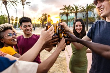 Genç bir grup çok ırklı arkadaş yaz partisinde soğuk biralarla kutlama yapıyorlar.