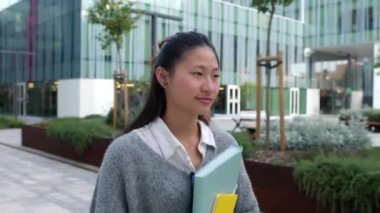 Üniversite kampüsündeki derslerden sonra dışarıda dolaşan Asyalı genç bir bayan. Eğitim ve milenyum insanları kavramı 