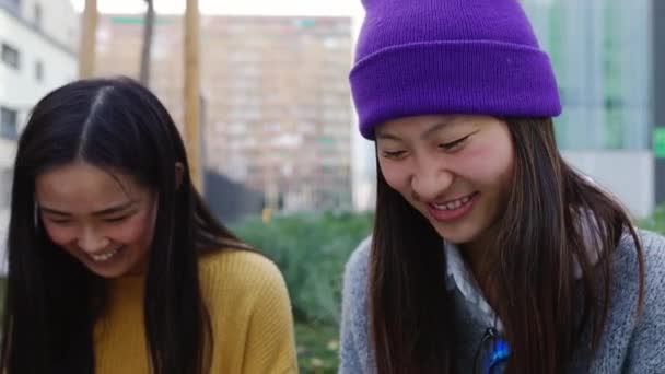 Χαρούμενοι Διαφορετικοί Ασιάτες Φοιτητές Που Χρησιμοποιούν Κινητό Τηλέφωνο Καθισμένοι Μαζί — Αρχείο Βίντεο