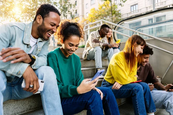 stock image Group of multiracial young people using mobile phone devices sitting outdoors. Millennial happy students addicted to social media app