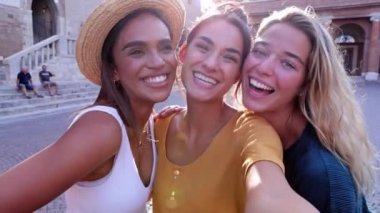 Birlikte kameraya gülümseyen üç farklı bayan arkadaş. Çok ırklı güzel kadınlar yaz tatilinde selfie çekerken birbirlerine sarılıp gülüyorlar. Arkadaşlık kavramı