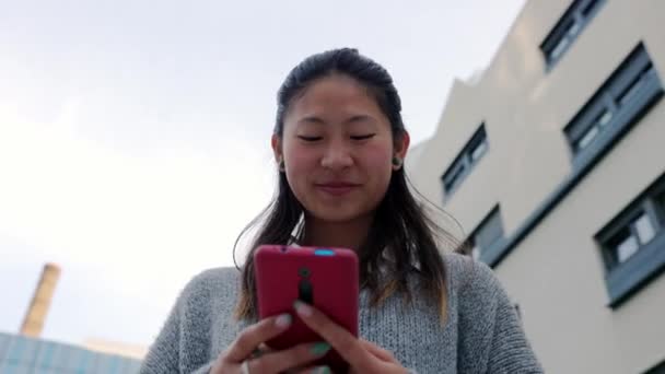 Gledelig Ung Asiatisk Kvinne Som Ler Med Mobiltelefon Bygata Tusenårig – stockvideo