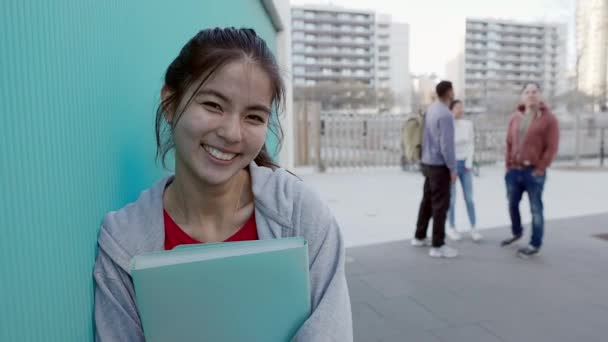 学校の壁にもたれている若いアジアの高校生の女性の笑顔の肖像画 教育と人々の概念 — ストック動画