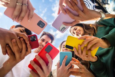 Cep telefonu kullanan bir grup genç dışarıda daireler çizerek ayakta duruyor. Sosyal medya uygulamasına bağımlı Milenyum arkadaşları, online platformda oyun oynuyorlar ya da bahis oynuyorlar.