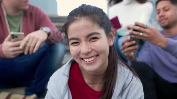 Arka Planda Akıllı Telefon Cihazı Kullanarak Kameraya Gülümseyen Asyalı Genç — Stok video