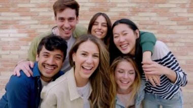 Dışarıda kameraya gülümseyen bir grup mutlu genç arkadaş. Birlikte eğlenen çok ırklı öğrencilerin portresi..