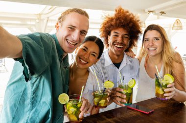 Yaz tatilinde plajda mojito içerken selfie çeken mutlu genç arkadaş grubu..