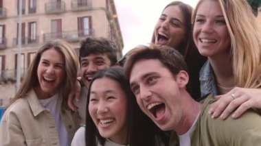 Çok kültürlü genç bir arkadaş grubu şehir sokaklarında birlikte eğleniyor. Çeşitli bin yıllık öğrenci erkek ve kadınlar bir arada durup dışarıda birbirlerine sarılıyorlar. Halk konsepti.