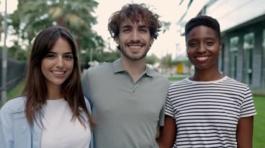 Dışarıda kameraya gülümseyen üç çok ırklı genç arkadaş. Neşeli milenyum insanları yaz aylarında birbirlerine sarılıyorlar. Çeşitlilik ve insanlar kavramı