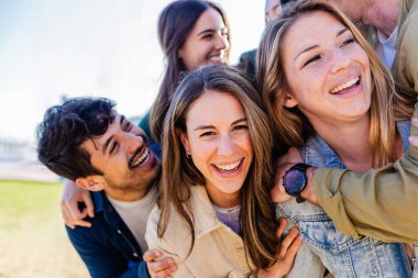 Çeşitli yetişkin arkadaş grupları dışarıda birbirlerine sarılırken eğleniyorlar. Neşeli milenyum insanları birlikte eğlenerek gülüyor. Topluluk ve arkadaşlık kavramı