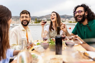 Bir grup genç arkadaş terasta yiyip içiyorlar. Milenyum insanları yaz partisi kutlamalarında birlikte yemek masasında eğleniyorlar. Arkadaşlık kavramı
