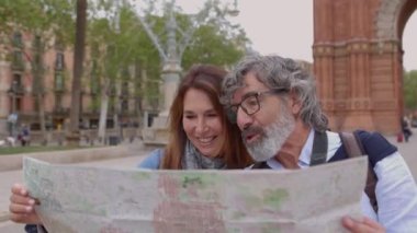 Tatilde Barselona 'yı ziyaret ederken elinde şehir haritası tutan mutlu yetişkin turist çifti. Evli, orta yaşlı bir adam ve kadın birlikte yaz tatilinin tadını çıkarmak için turistik bir yer arıyorlar. Emeklilik