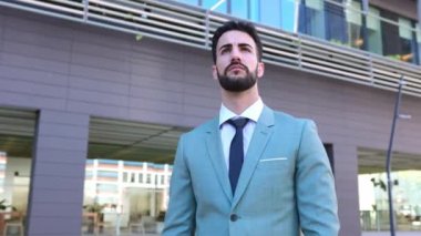 Kendine güvenen bir işadamı modern mali yapı ofisinin önünde duruyor yeni hedefler düşünüyor, gelecekteki projeleri ya da iş başarılarını hayal ediyor..